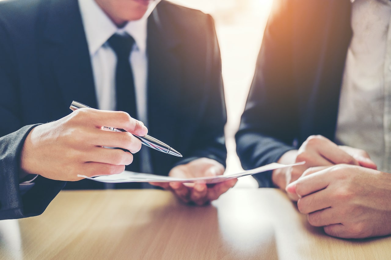 two pairs of hands gesture at a contract containing a force majeure clause