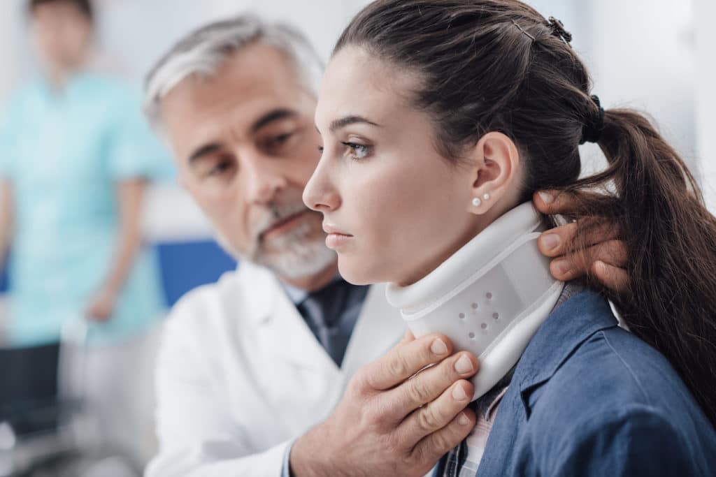 doctor fits woman's neck with a neck brace