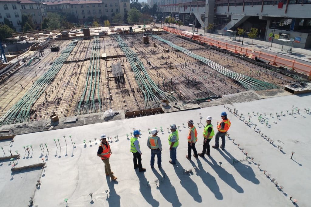 Seven construction men overlooking an empty site